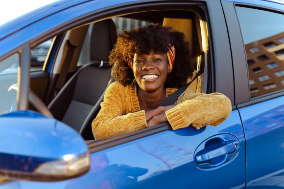 Happy African American woman in blue car. 