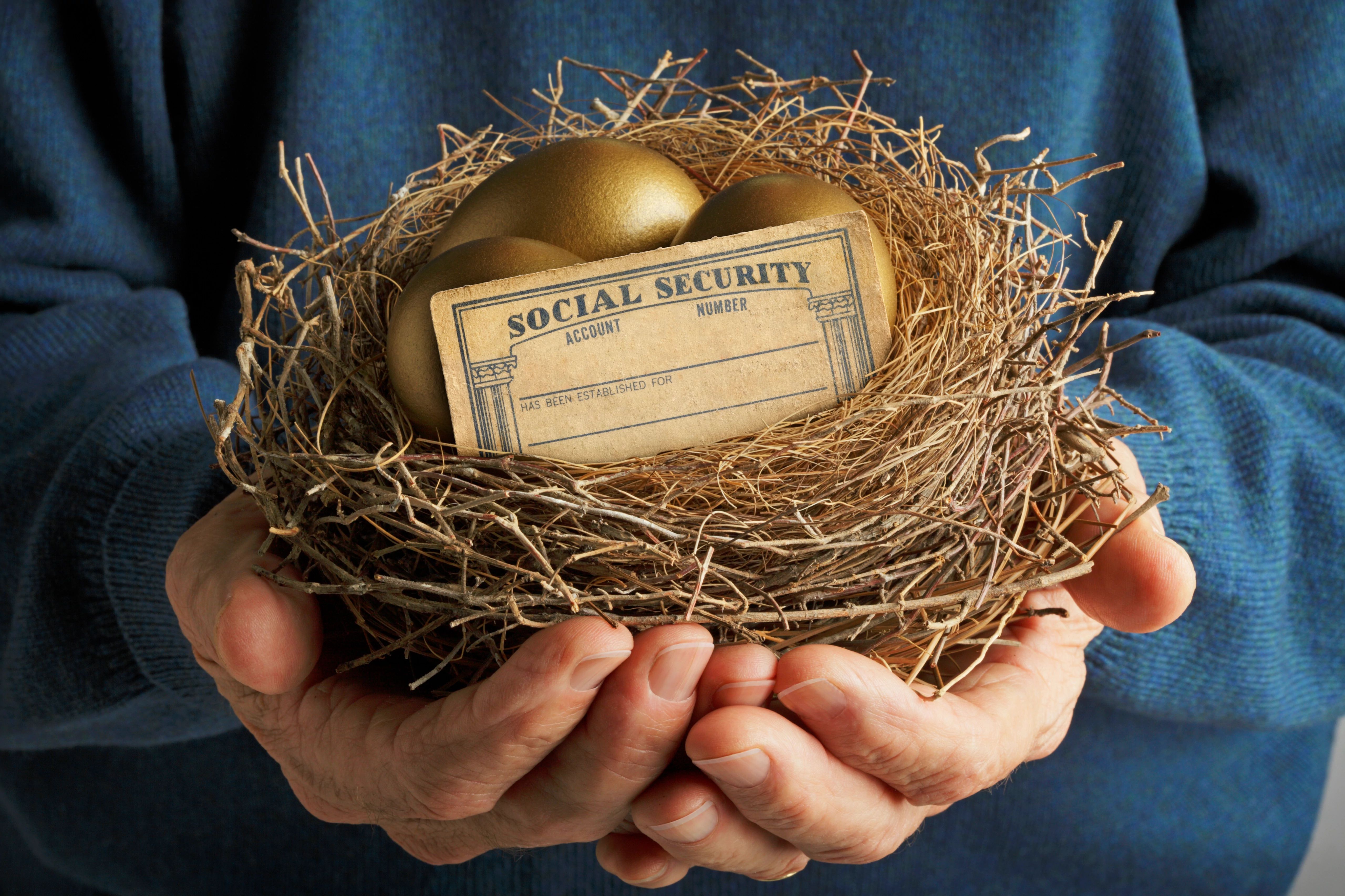 Hands holding a birds next filled with golden eggs and a Social Security card.